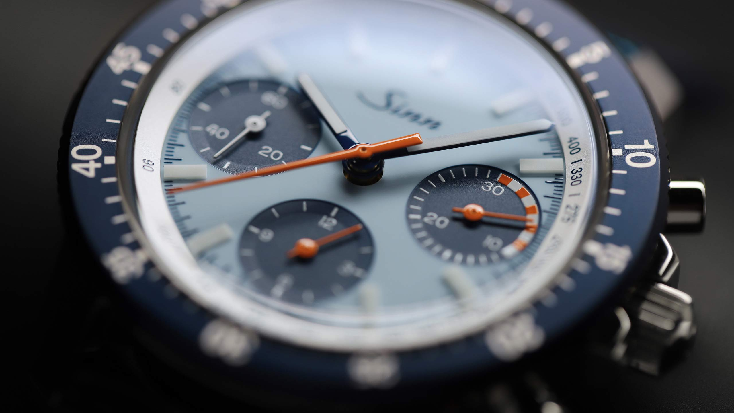                       Nahaufnahme der Vorderseite der Sinn 103 St Sa Ty Hd H – ein blauer Chronograph mit hellem, eisblauem Zifferblatt, blauer Drehlünette und orangefarbenen Zeigern.
                  