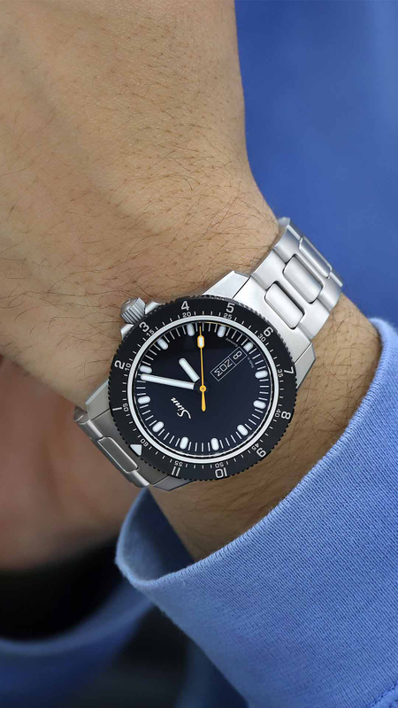 Sinn 105 St Sa avec cadran noir, trotteuse orange et bracelet en acier inoxydable portée au poignet.