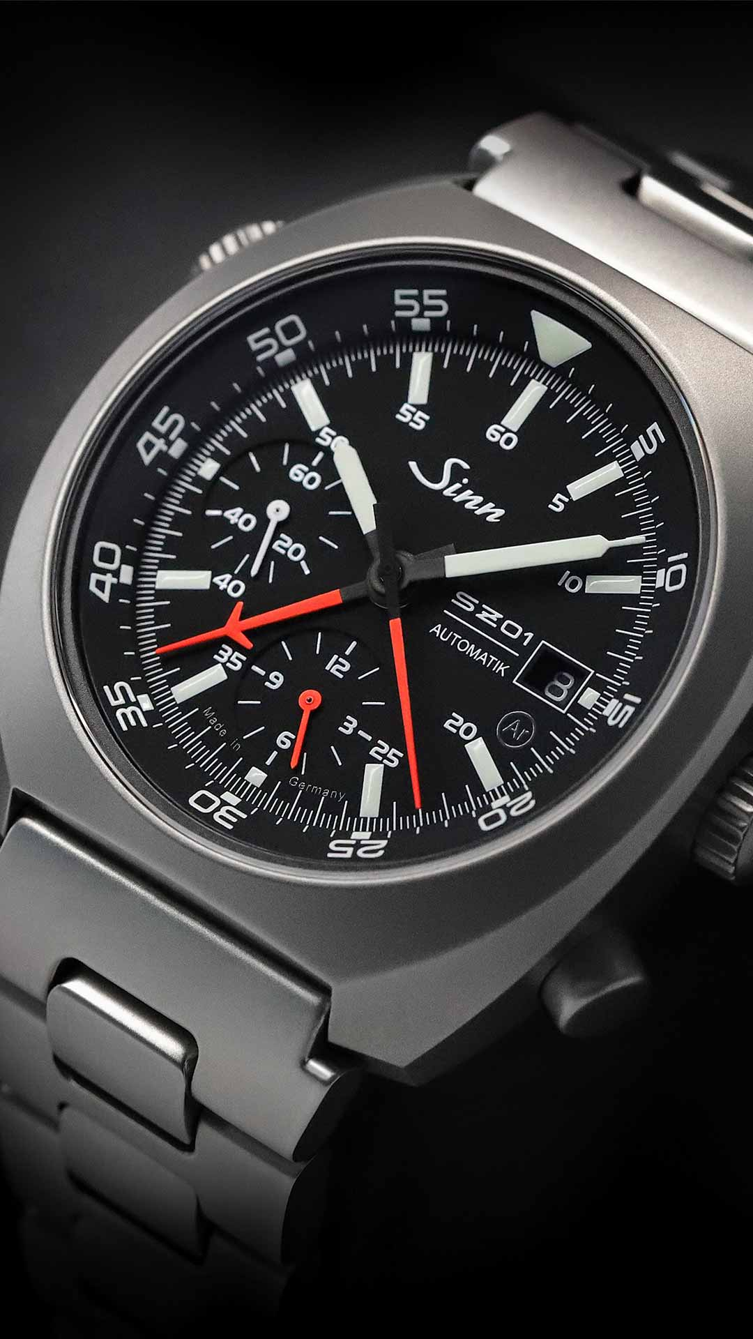 Sinn 140 St Automatik-Chronograph mit schwarzem Zifferblatt, roten und weißen Zeigern sowie Edelstahlarmband.
