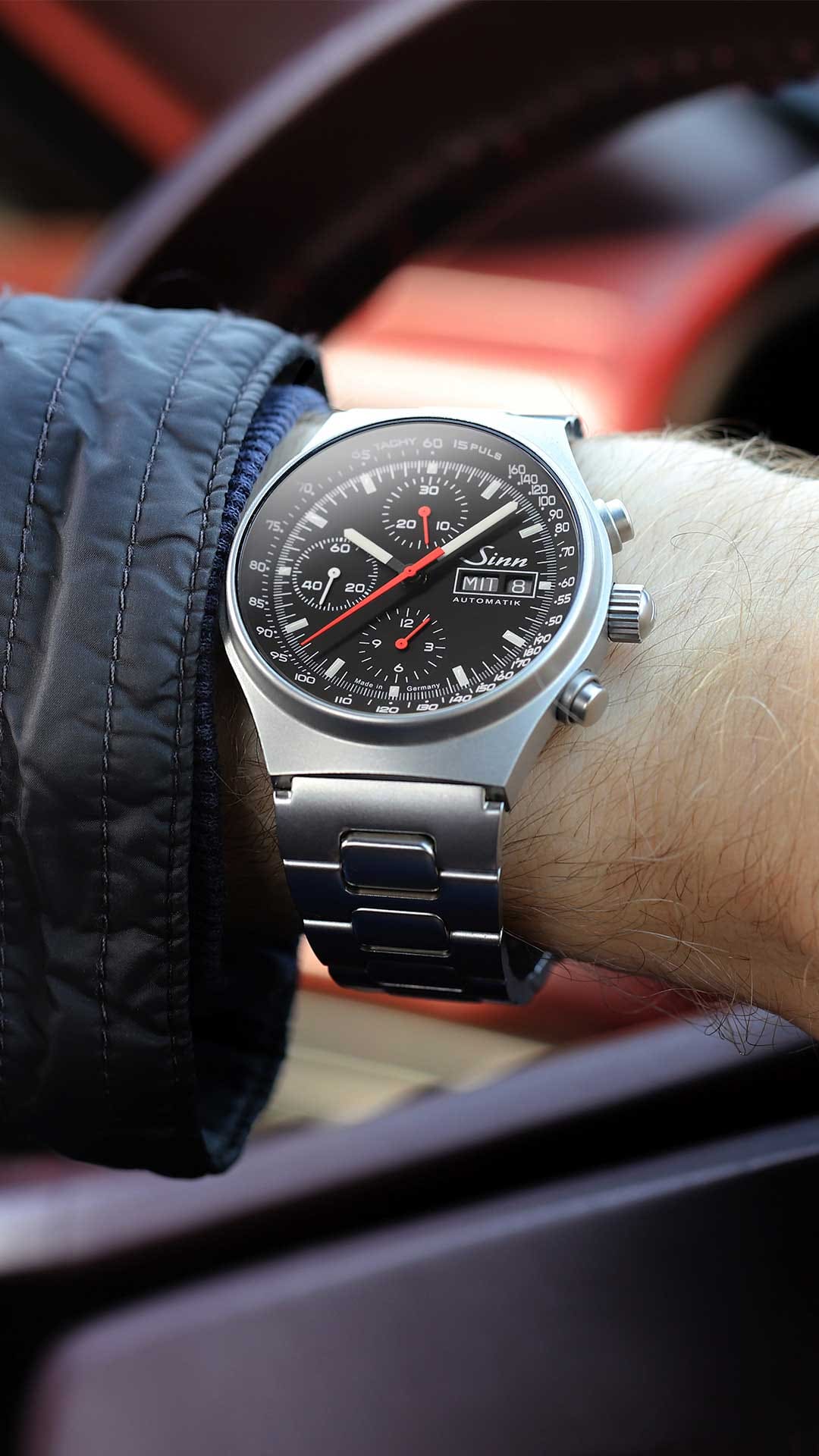Sinn 144 St Sa automatic chronograph with stainless steel case, black dial, white and red hands, and stainless steel bracelet on the wrist.