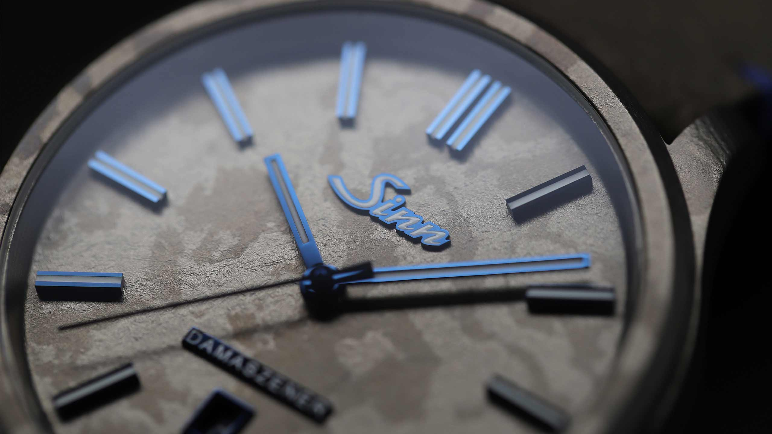                       Close-up of the Sinn 1800 TITANDAMASZENER with textured dial and blue indices.
                  