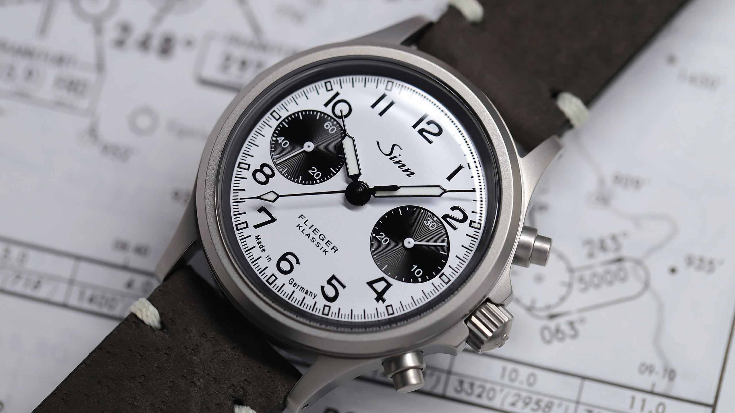                       Sinn 356 Flieger Klassik W mit weißem Zifferblatt, schwarzen Totalisatoren und grauem Lederband in Nahaufnahme.
                  