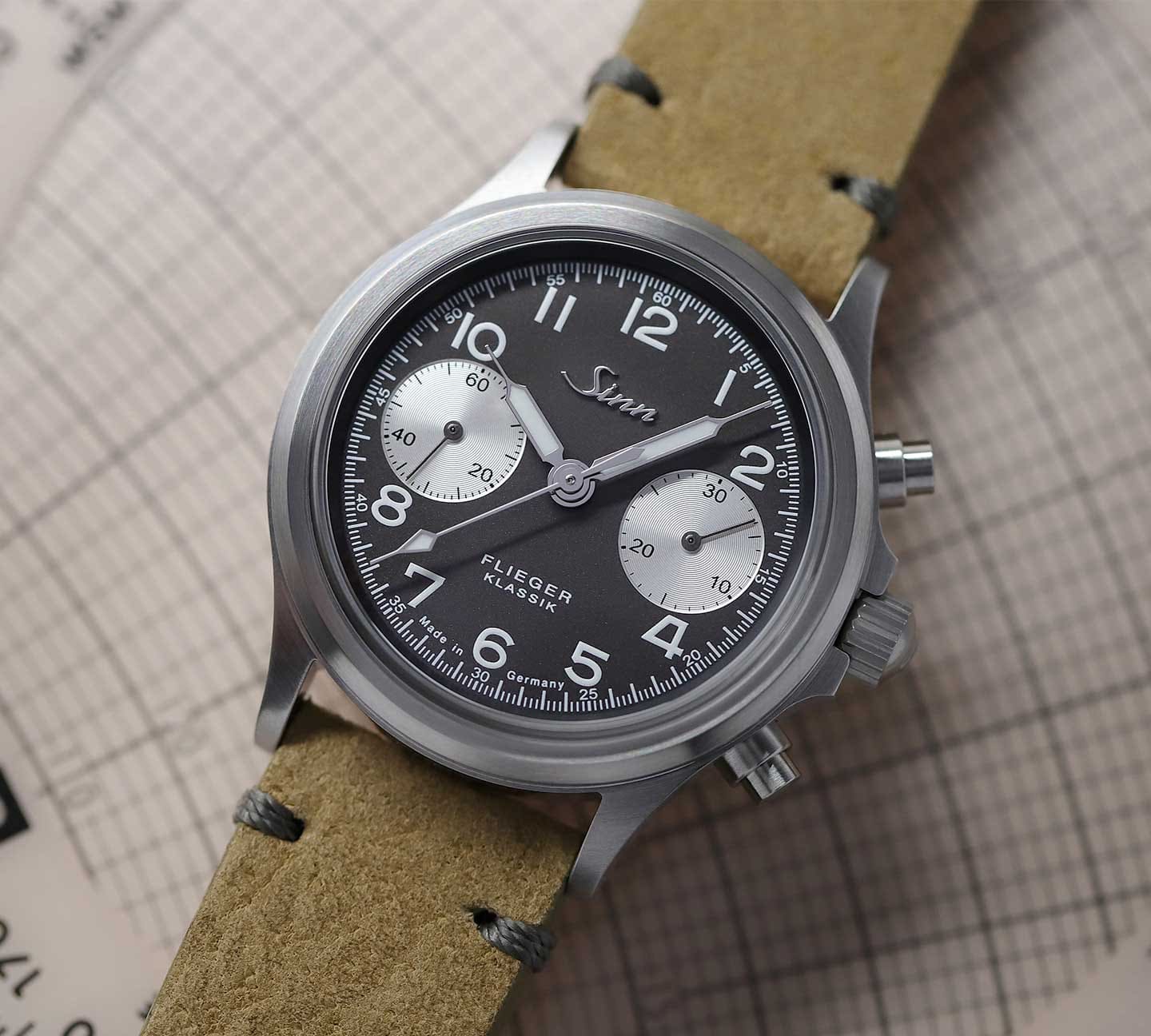 Sinn 356 Flieger Klassik Jubiläum mit schwarzem Zifferblatt und silbernen Totalisatoren am hellbraunen Lederarmband, Nahaufnahme.