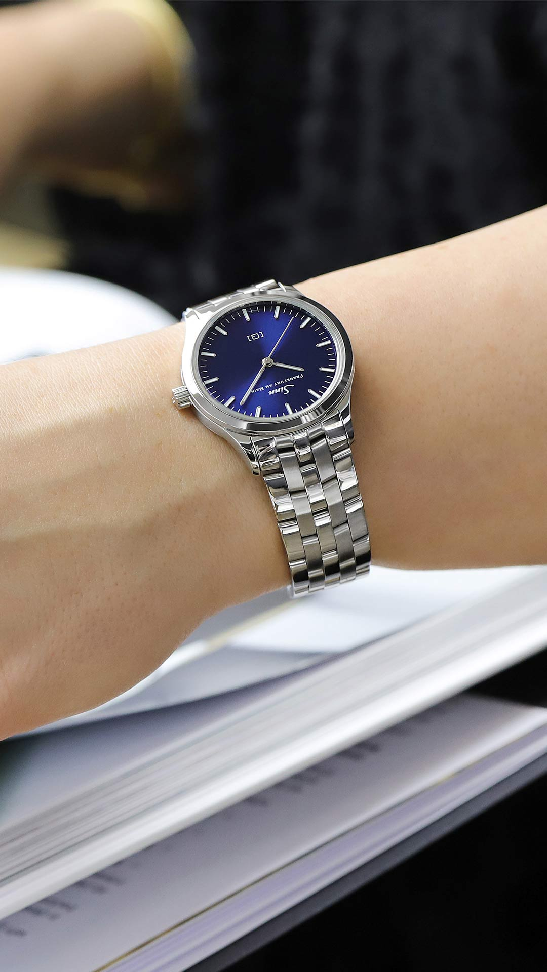 Sinn 434 St B mit blauem Sonnenschliff-Zifferblatt am Edelstahlarmband am Handgelenk getragen.