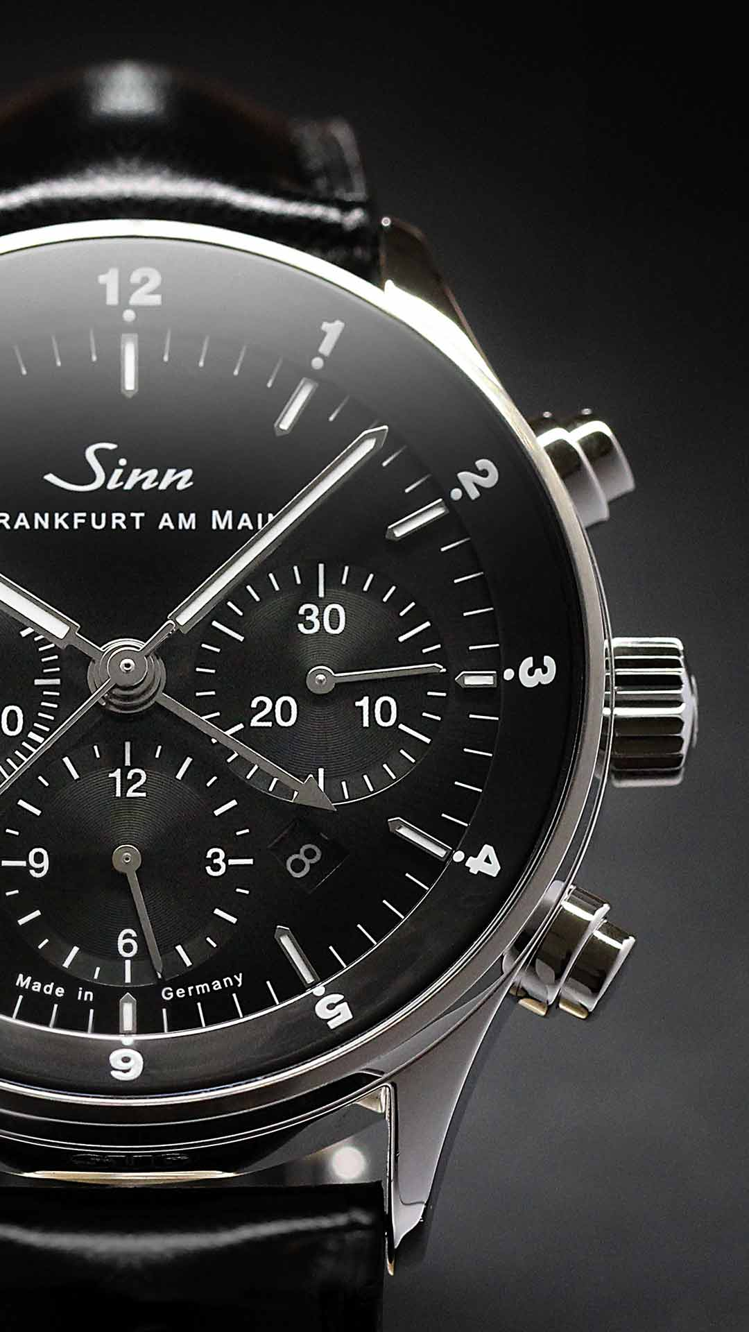 Nahaufnahme der Sinn 6099 mit schwarzem Zifferblatt, Chronographenzählern und Lederarmband.