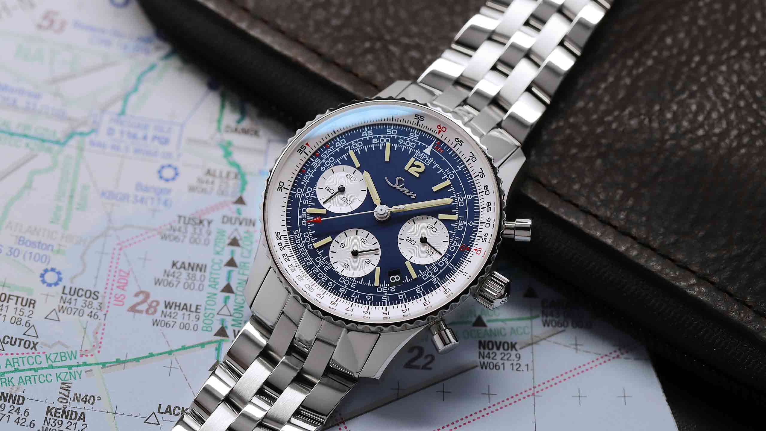                       Sinn 903 St BE II chronograph with blue dial on map background.
                  