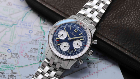                       Chronographe Sinn 903 St BE II avec cadran bleu sur une carte.
                  