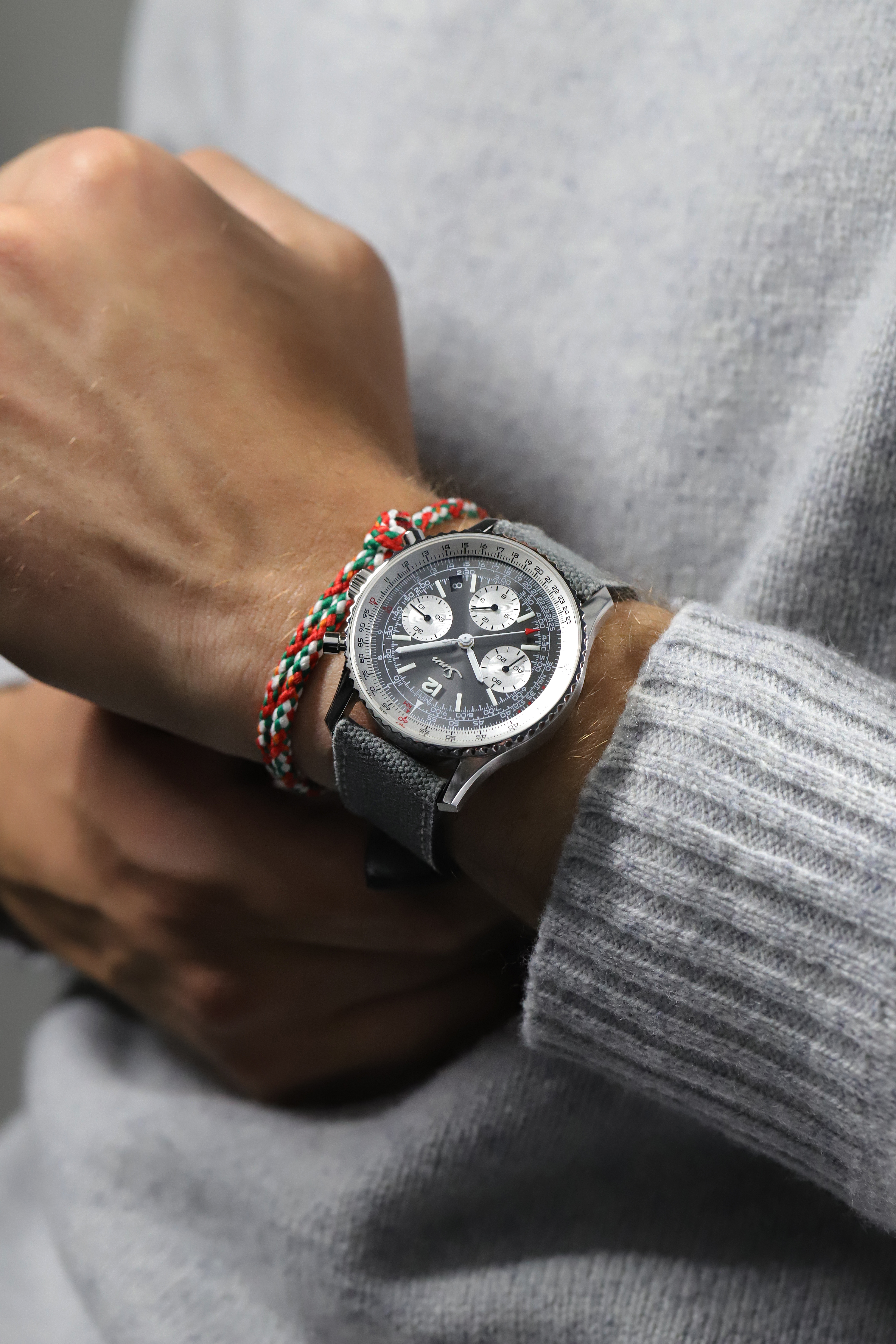 Sinn chronograph with anthracite dial, slide rule bezel, and grey textile strap worn on a wrist.