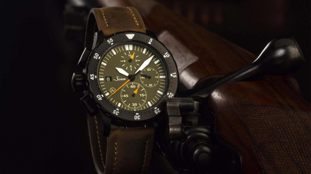                       Sinn U1000 Hunting Watch 3rd Edition with olive dial, leaning against a hunting rifle.
                  
