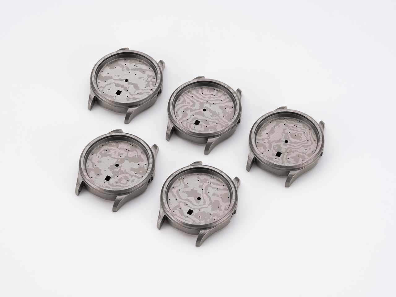 Five cases of the Sinn 1800 TITANDAMASZENER made from patterned titanium Damascus steel on white background