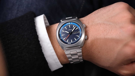                       Sinn 240 St GZ with blue dial, internal tide bezel and stainless-steel bracelet, worn on the wrist with a dark jacket.
                  