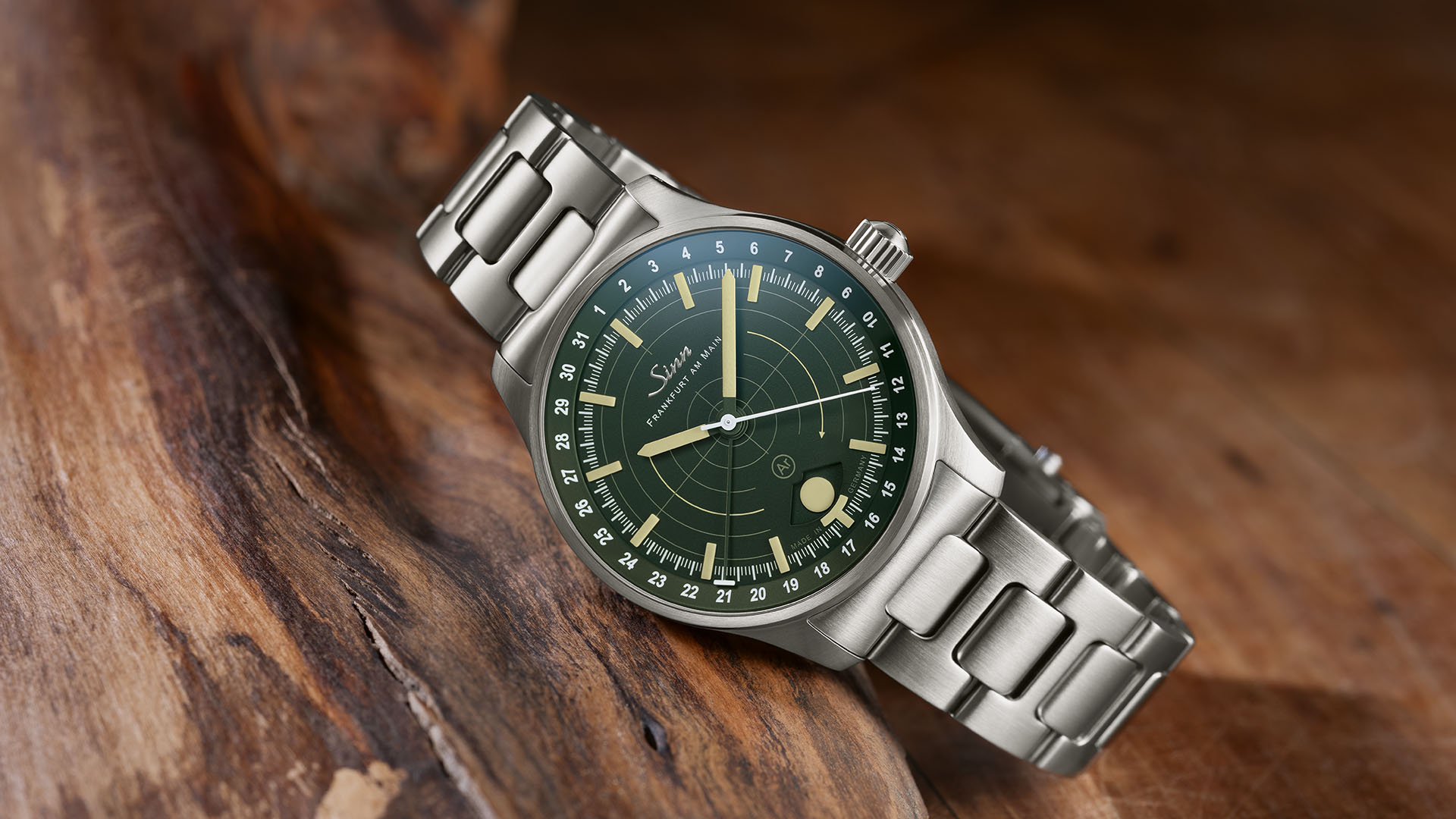                       Stainless steel wristwatch with a green dial and metal bracelet, placed on a rustic wooden surface
                  