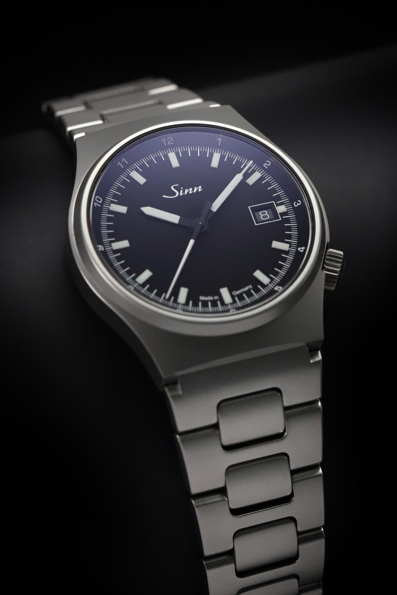 Wristwatch with a black dial and metal bracelet displayed on a dark background.