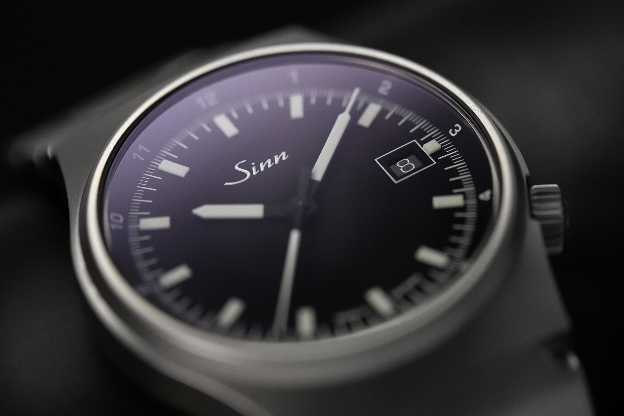 Close-up of a wristwatch with a black dial, date display, and clean hour markers.