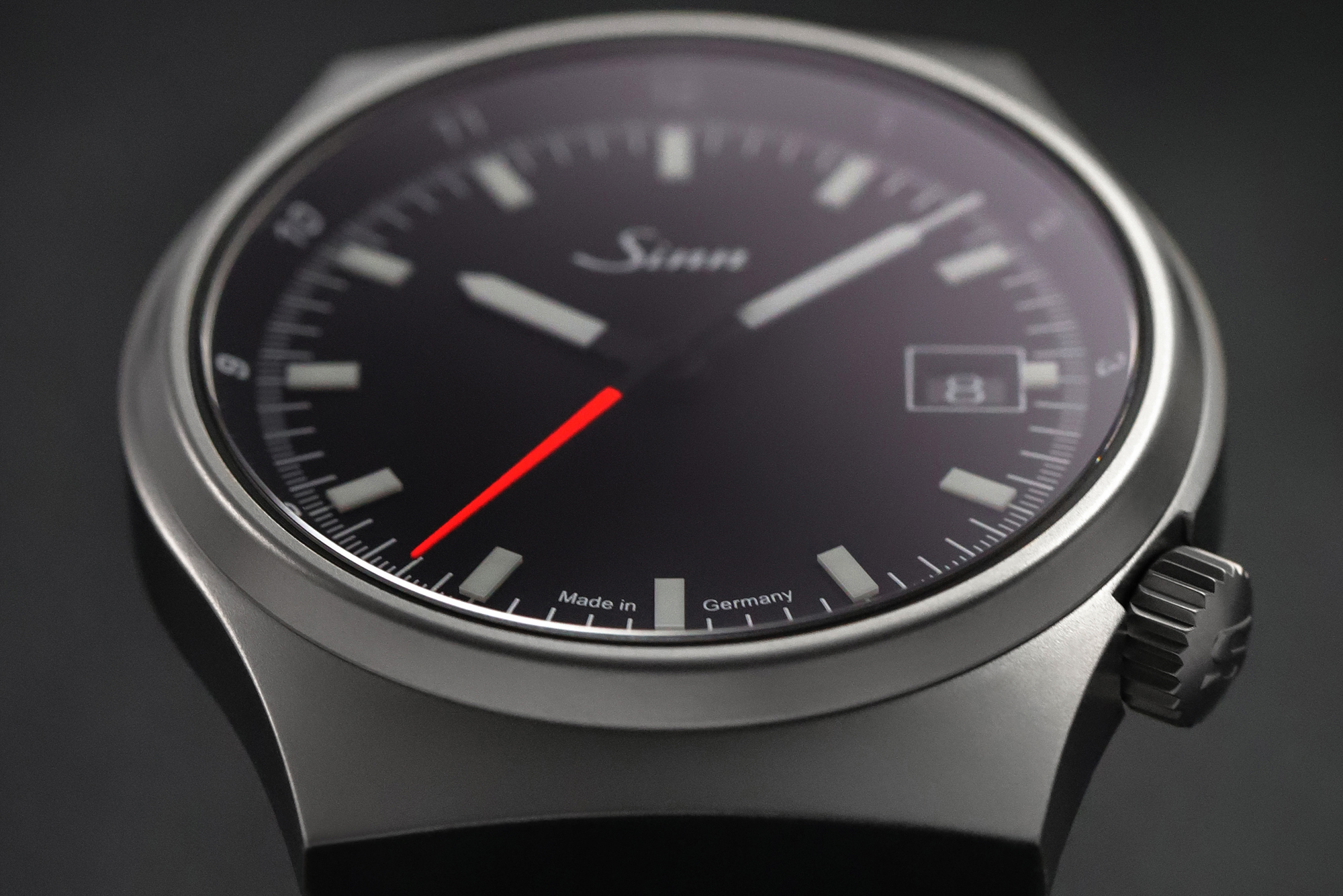                       Gros plan d’une montre-bracelet avec cadran noir, trotteuse rouge et affichage de la date.
                  