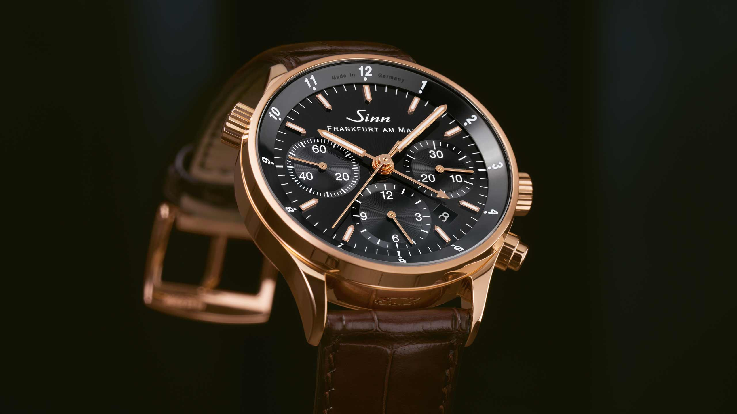 Elegant Sinn 6000 rose gold wristwatch with a black dial and rose gold case, presented with a brown leather strap.