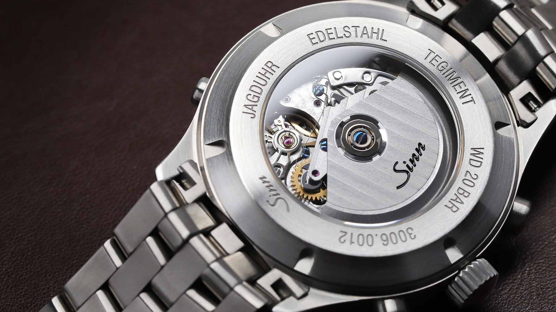 Sinn-Uhr mit Sichtboden und Edelstahlgehäuse auf dunklem Untergrund.