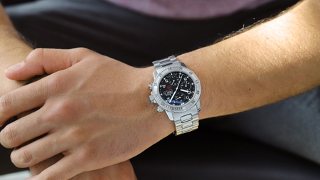                       Sinn 206 St Ar mit schwarzem Zifferblatt, Edelstahlgehäuse und Massivband, getragen am Handgelenk vor dunklem Hintergrund.
                  