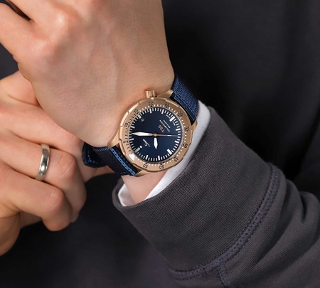 Sinn T50 GOLDBRONZE B on the wrist with blue textile strap, worn with a dark sweater.