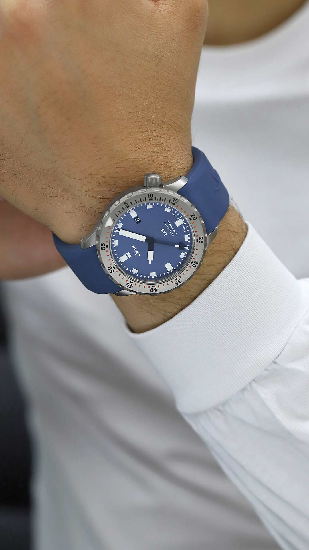 Sinn U1 B diver’s watch with blue dial and blue silicone strap on the wrist.
