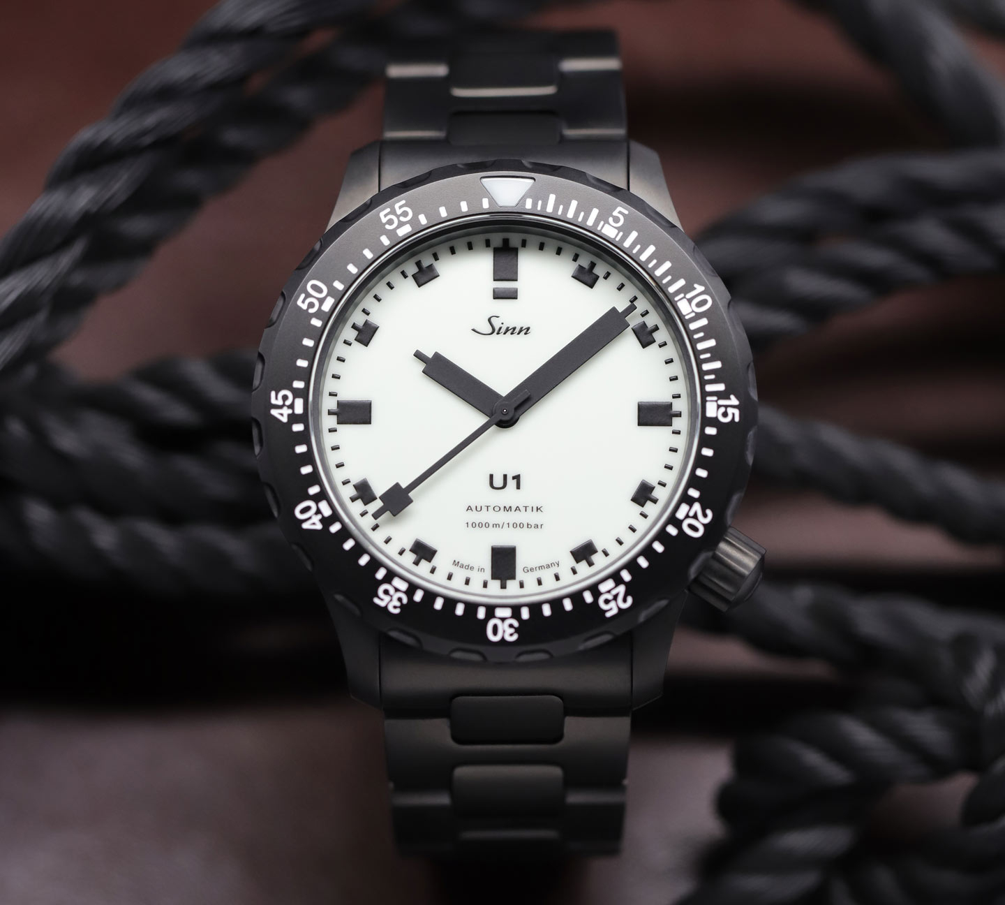 U1 S L with black case and white dial on a black metal bracelet, set against dark ropes.