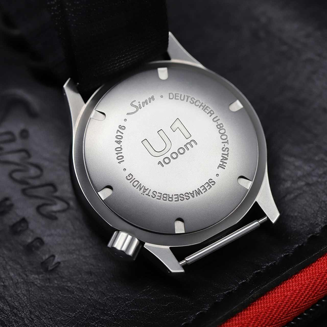 Engraved case back of the Sinn U1 with model reference, depth rating and submarine steel indication, with black leather strap