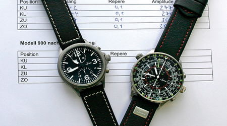Sinn 756 (links) und Multifunktionschronograph 900 (rechts) auf DEKRA-Testprotokollen; beide Uhren mit schwarzem Zifferblatt, der 900 mit farbigen Skalen und Armband mit roten Nähten.